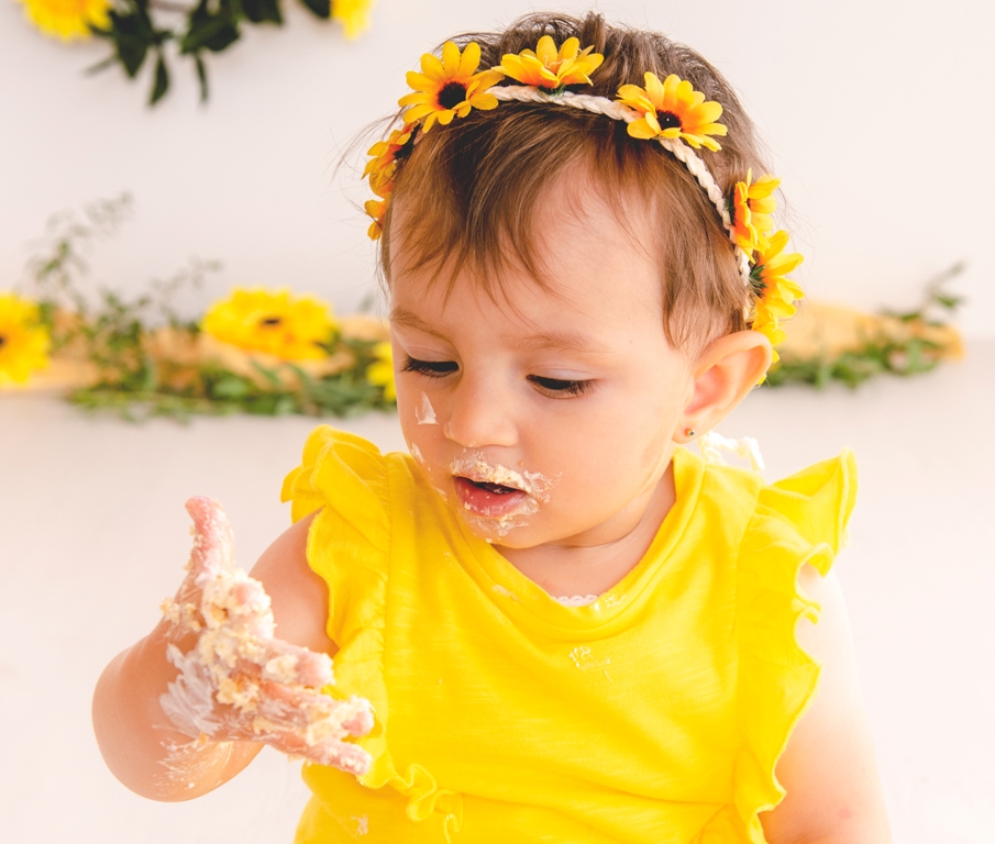 bambina che gioca con la torta durante il suo servizio fotografico per il primo compleanno o smash cake