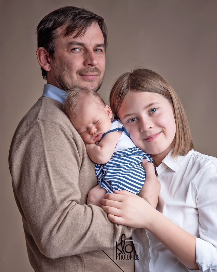  papà e sorella tengono in braccio la neonata per le prime foto durante la sessione fotografica di famiglia presso fotografa klophotokids