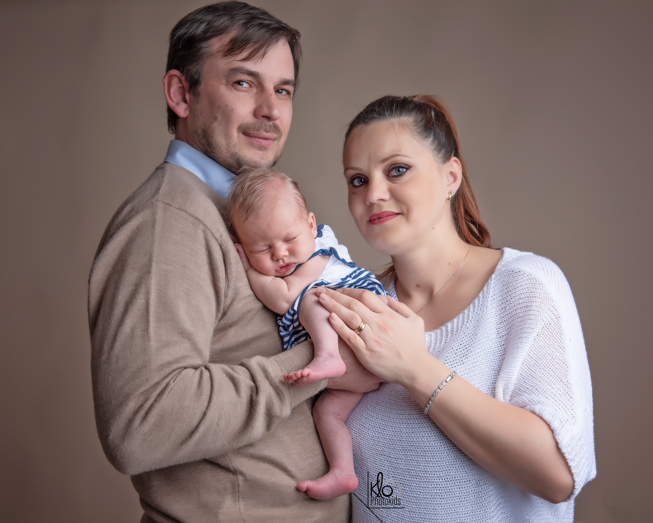  papà e mamma tengono in braccio la neonata per le prime foto durante la sessione fotografica di famiglia presso fotografa klophotokids