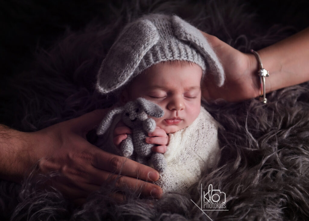 Neonata in posa per la sua sessione fotografica newborn.
Tiene stretto tra le mani un piccolo orsetto