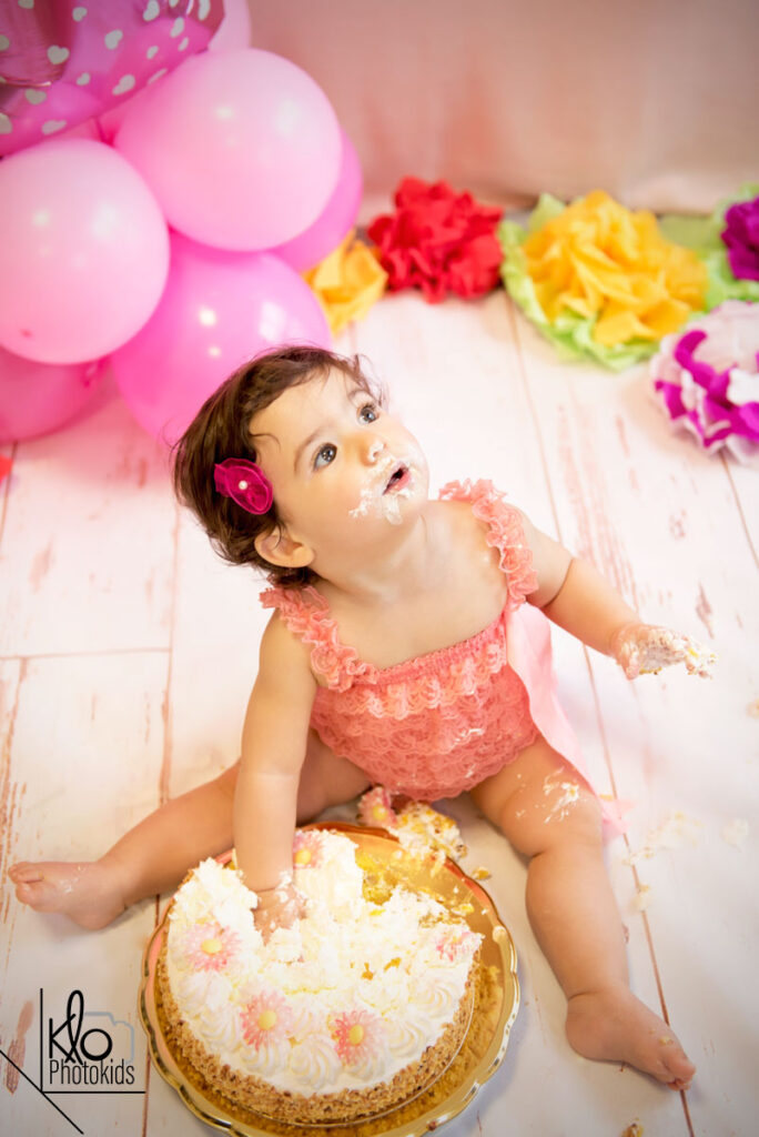 bambina che gioca con la torta durante il suo servizio fotografico per il primo compleanno o smash cake
