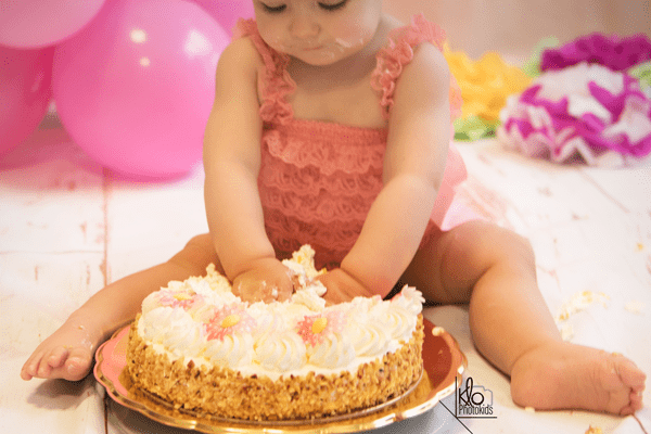 bambina che gioca con la torta durante il suo servizio fotografico per il primo compleanno o smash cake