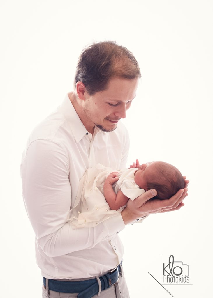 papà tiene in braccio la sua neonata per le prime foto durante la sessione fotografica