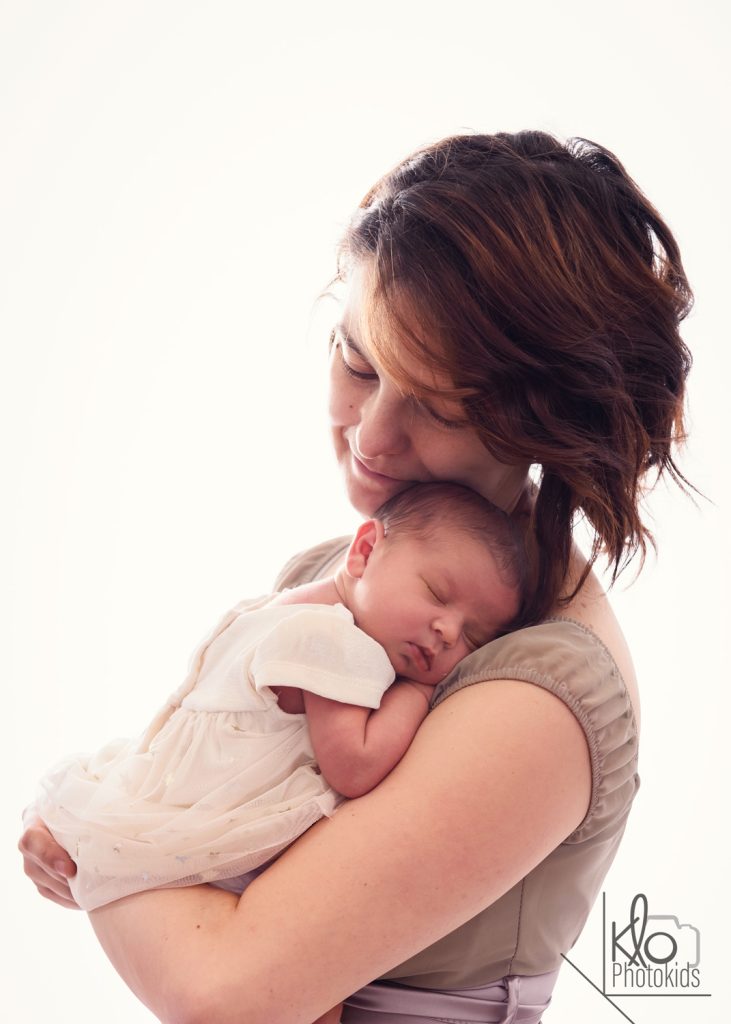 mamma tiene in braccio la sua neonata per le prime foto durante la sessione fotografica